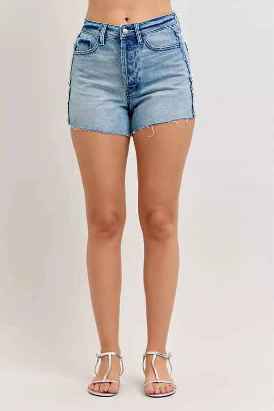Judy Blue HW Rigid Magic Cut-Off Denim Shorts with raw side seams, styled with distressed denim and frayed edges.